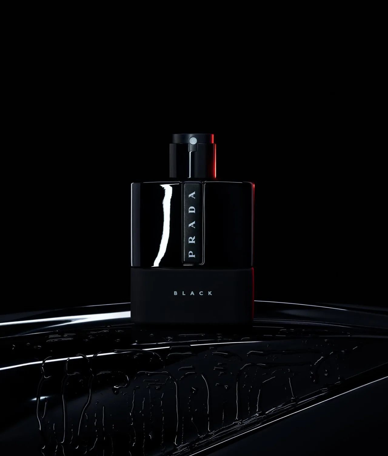 A sleek black bottle of Prada Black perfume is displayed against a dark background, with subtle reflections and highlights emphasizing its glossy surface.
