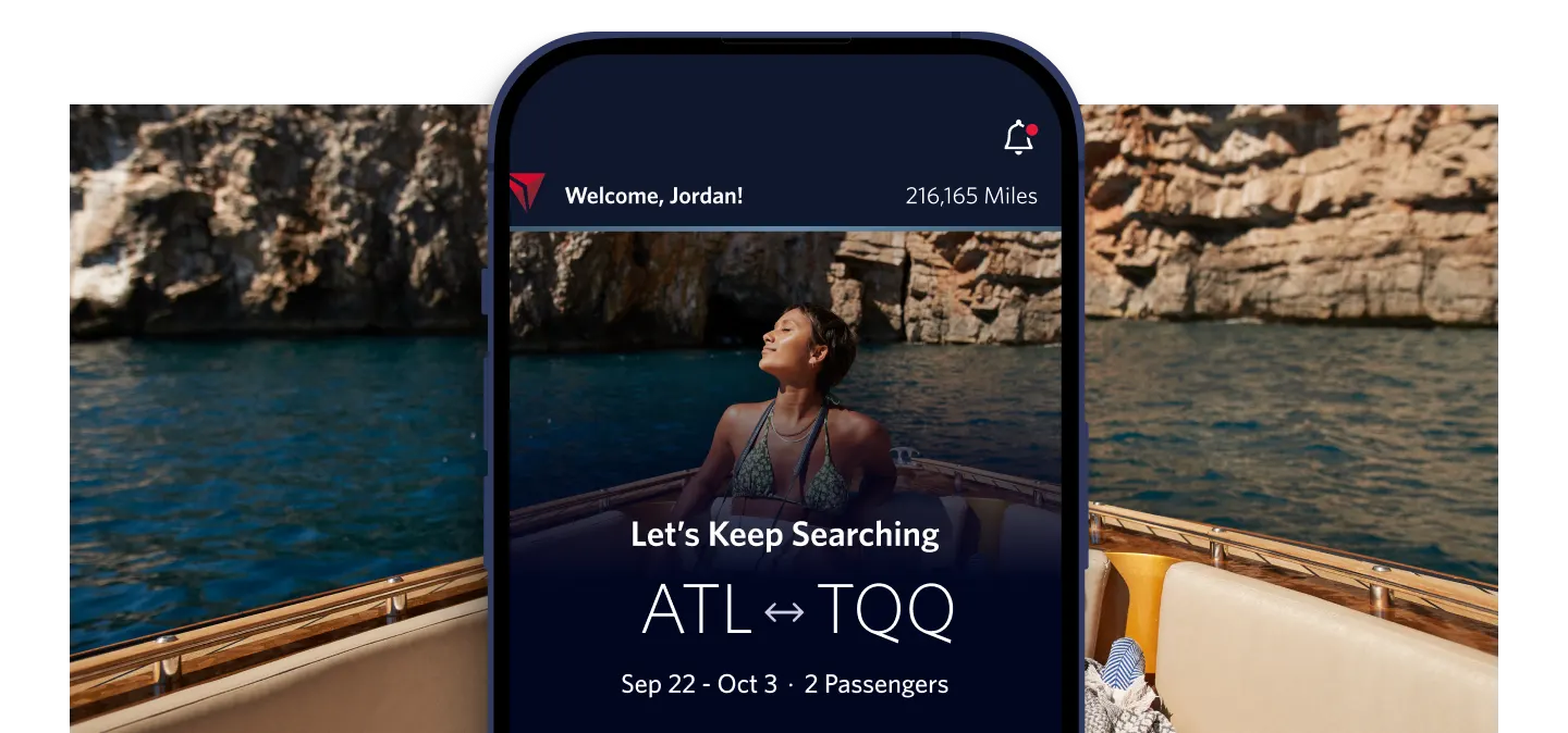 A phone screen displays a flight search from ATL to TQQ for two passengers, September 22 to October 3. In the background, a person enjoys a boat ride on clear blue water near rocky cliffs.
