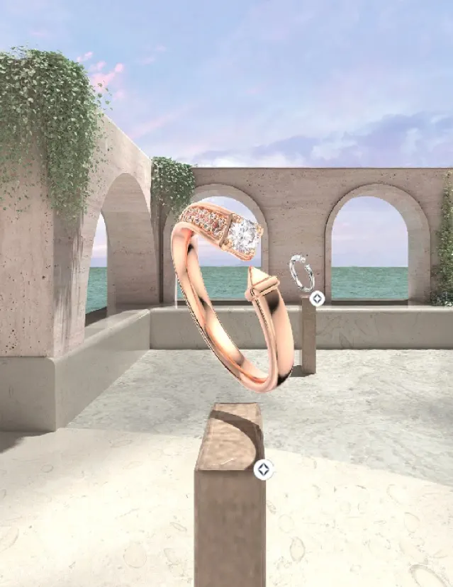 A rose gold diamond ring is displayed on a pedestal in an open, arch-lined courtyard with vines and a view of the ocean under a partly cloudy sky. Another ring is visible on a distant pedestal.