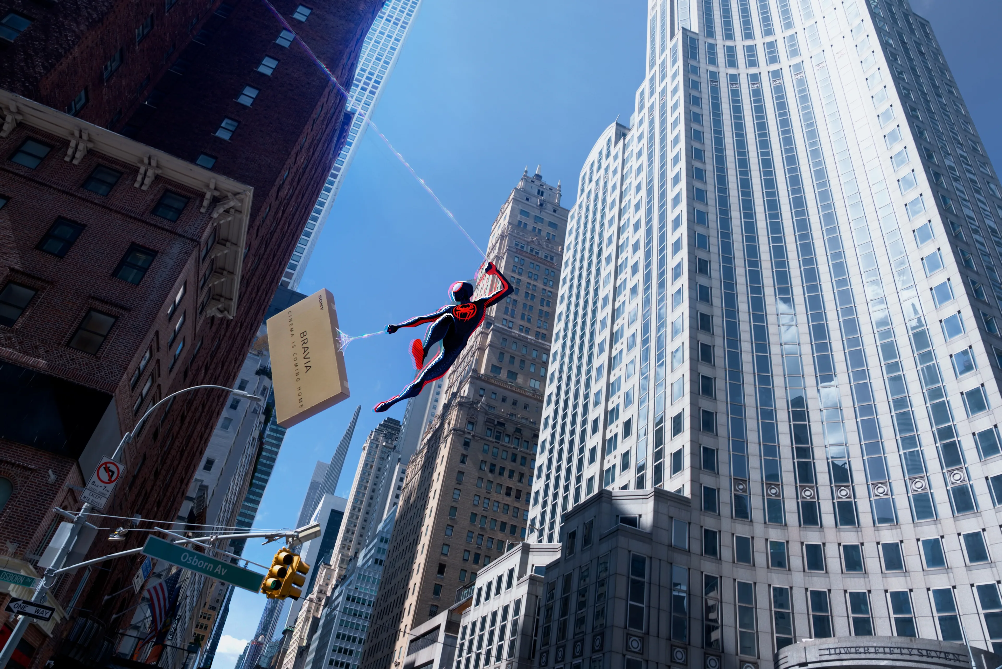 Spider-Man swings on a web between tall skyscrapers in a bright cityscape, with blue sky and sunlight reflecting off the glass buildings.