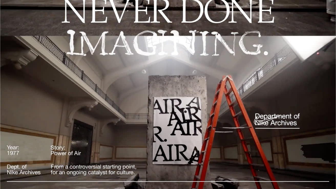 A tall concrete slab painted with the word AIR stands in an ornate hall beside an orange ladder. Large white text reads, NEVER DONE IMAGINING. Smaller text references Nike Archives, 1977, and a story called Power of Air.
