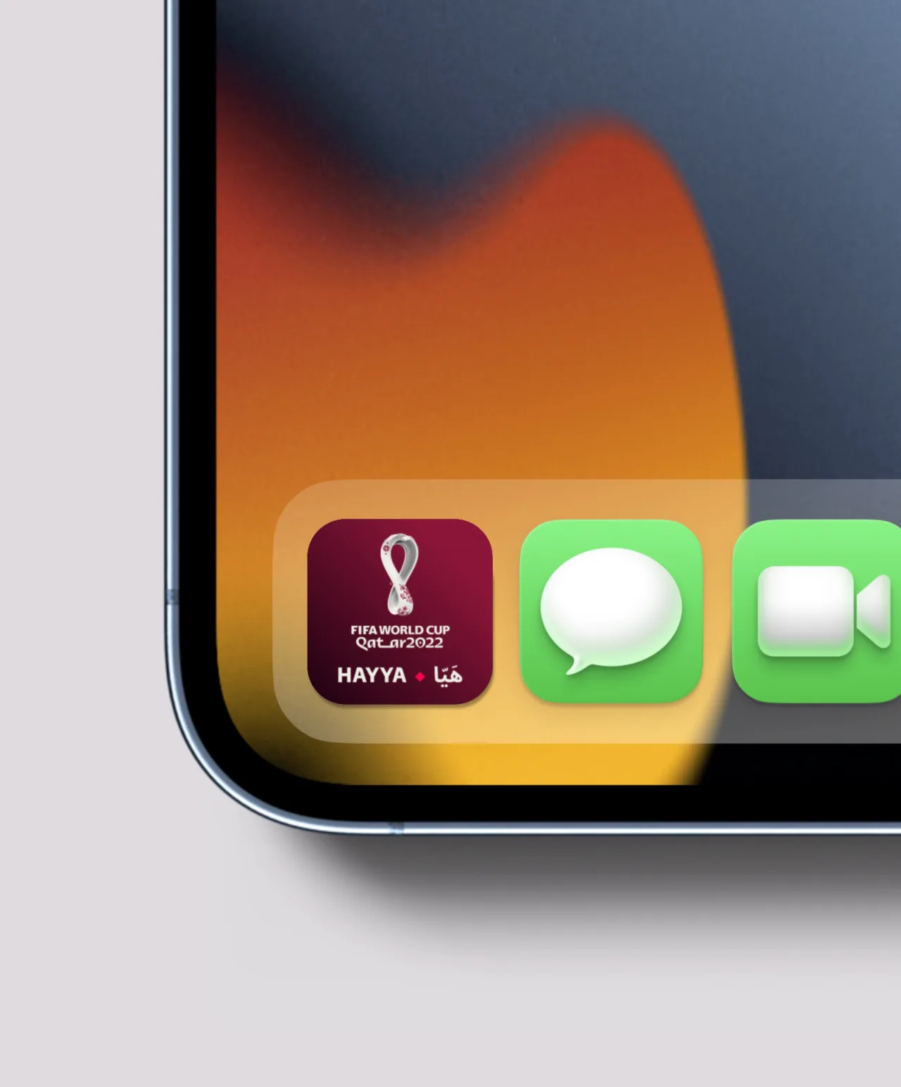 Close-up of a smartphone screen showing app icons, including the FIFA World Cup Qatar 2022 HAYYA app, Messages app, and FaceTime app, on a background with orange and black gradients.