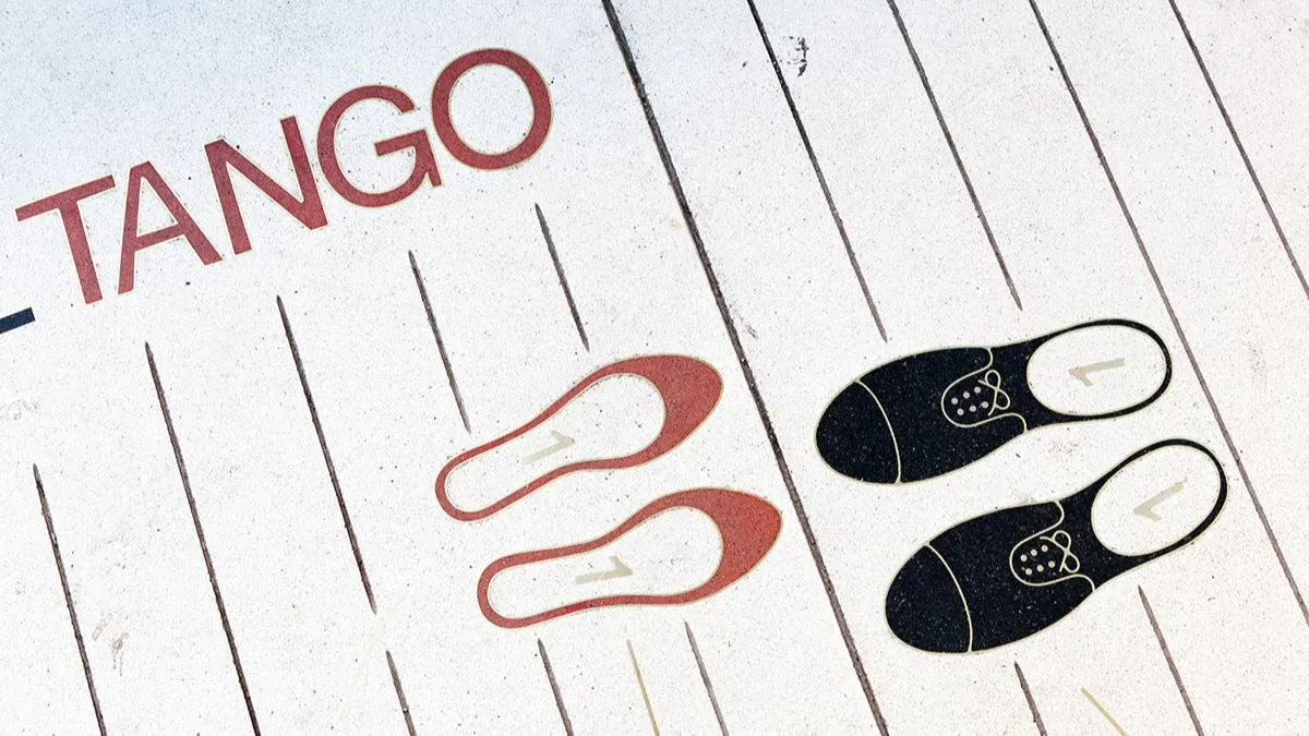 Illustration of red womens shoes and black mens shoes on a white floor with the word TANGO, showing dance step positions for partners.