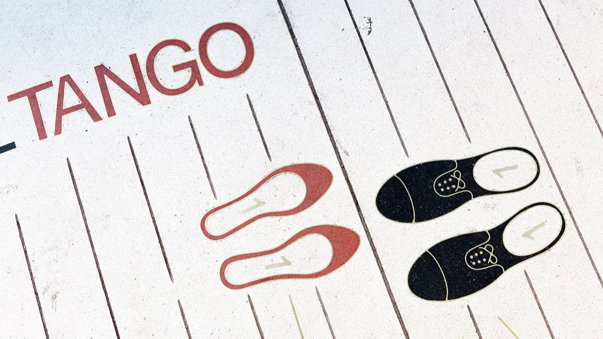 Illustration of red womens shoes and black mens shoes on a white floor with the word TANGO, showing dance step positions for partners.