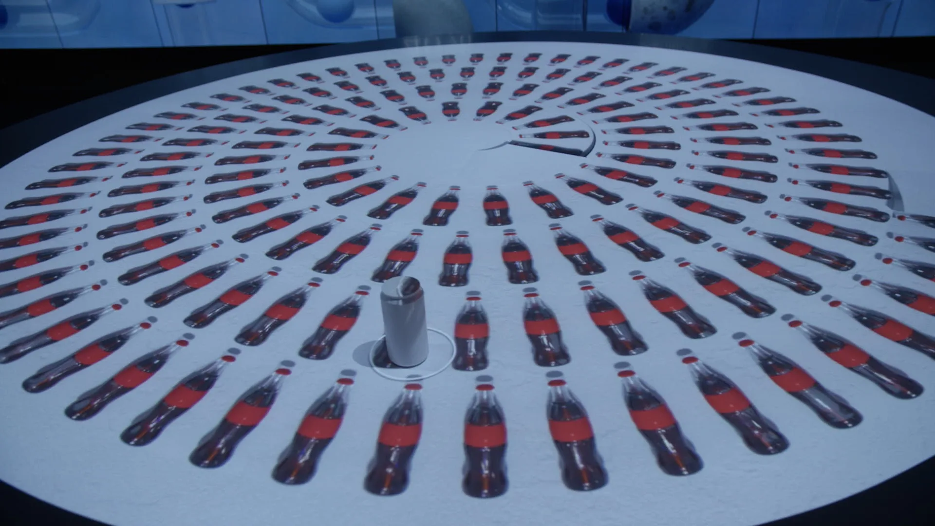 A white circular table displays dozens of Coca-Cola bottles arranged in concentric circles, with a single white cylindrical object standing upright near the center.