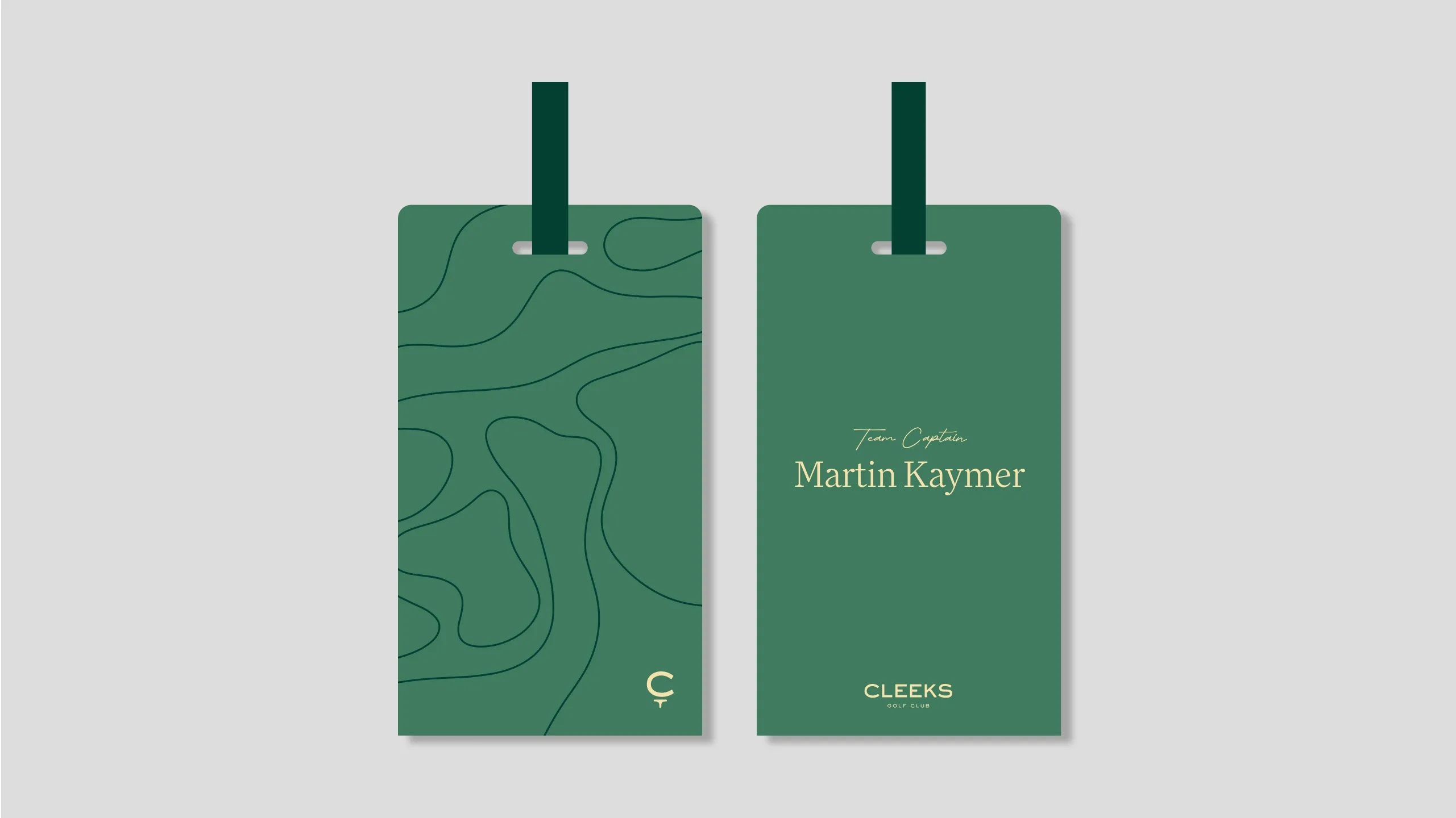 Two green rectangular tags with dark green ribbons. The left tag has abstract contour lines and a small C and T at the bottom. The right tag displays Team Captain Martin Kaymer and CLEEKS Golf Club in gold text.