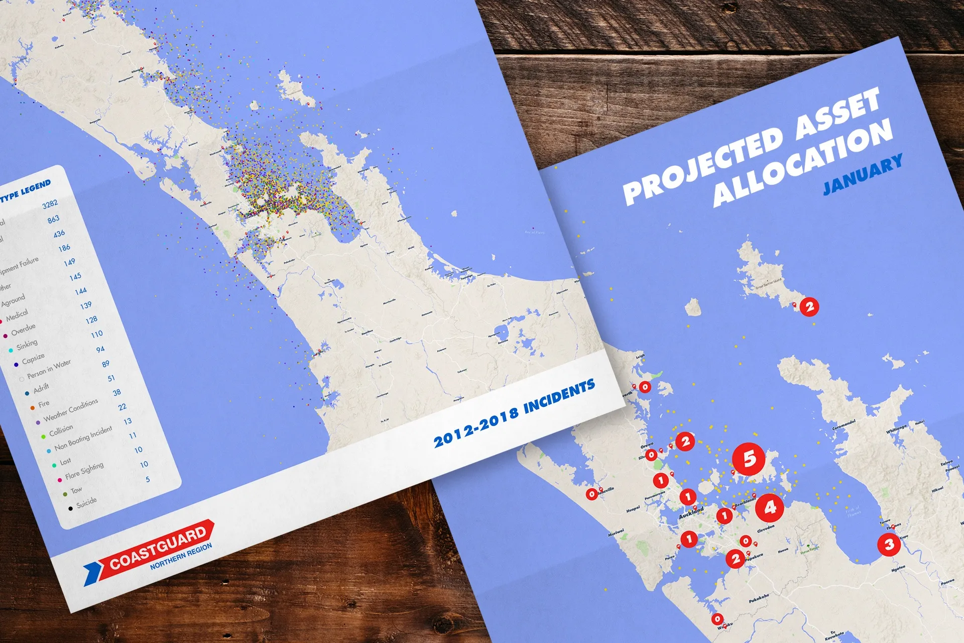 Two Coastguard maps of a coastal region show incident data and projected asset allocation. One map features colored incident dots and a legend; the other highlights numbered red circles for asset locations. Maps are on a wooden surface.