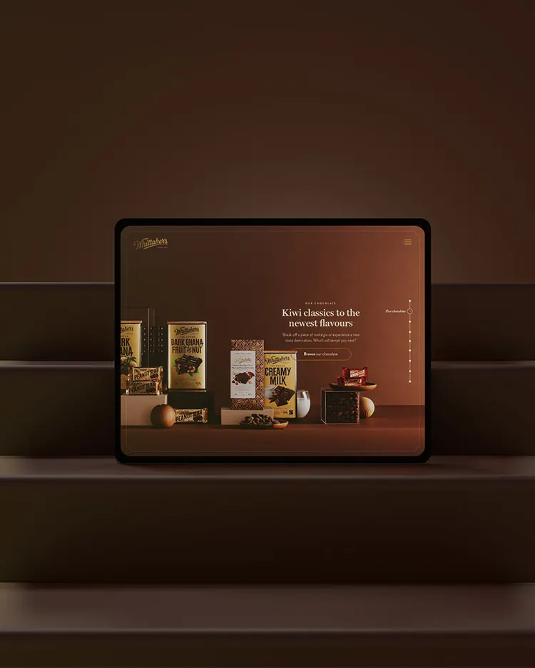 A tablet displays a website featuring Kiwi confectionery products, including chocolate bars and cookies, set against a brown background with product packaging visible and a headline introducing new flavors.