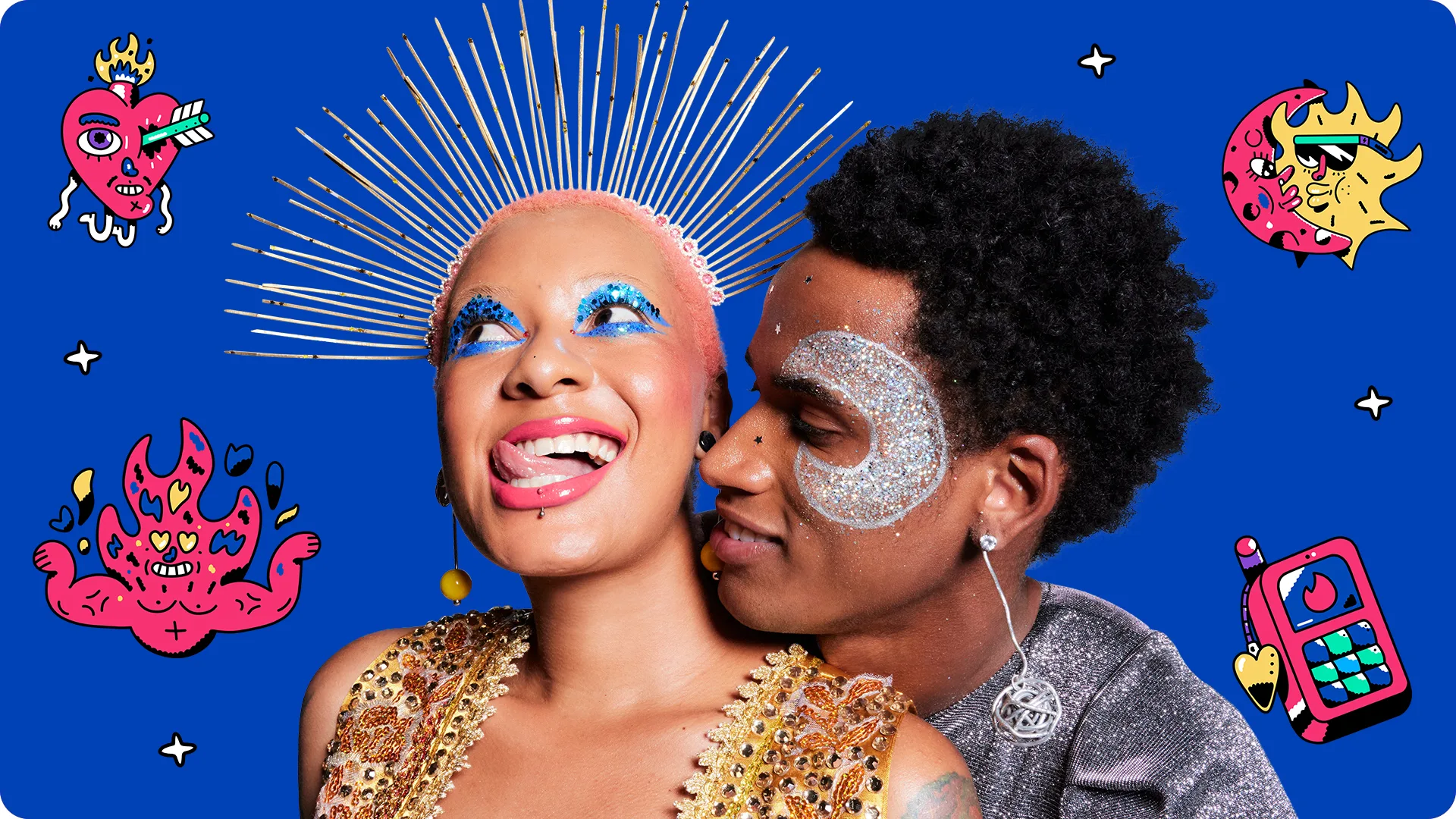 Two people in glittery, colorful makeup and festive outfits pose playfully against a blue background with whimsical, illustrated hearts, flames, and a phone. One person smiles widely while the other leans close, both expressing joy.