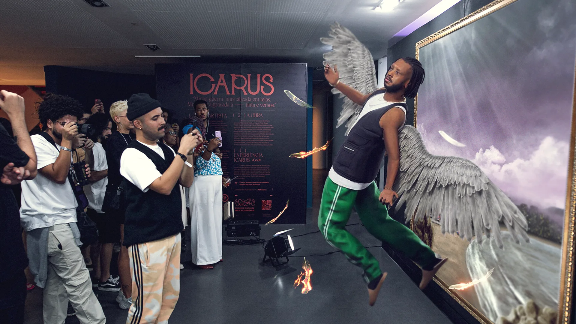 A man poses as if flying with angel wings in front of a large painting, surrounded by people taking photos. The scene is part of an art installation themed “ICARUS,” with some fiery visual effects near his feet.