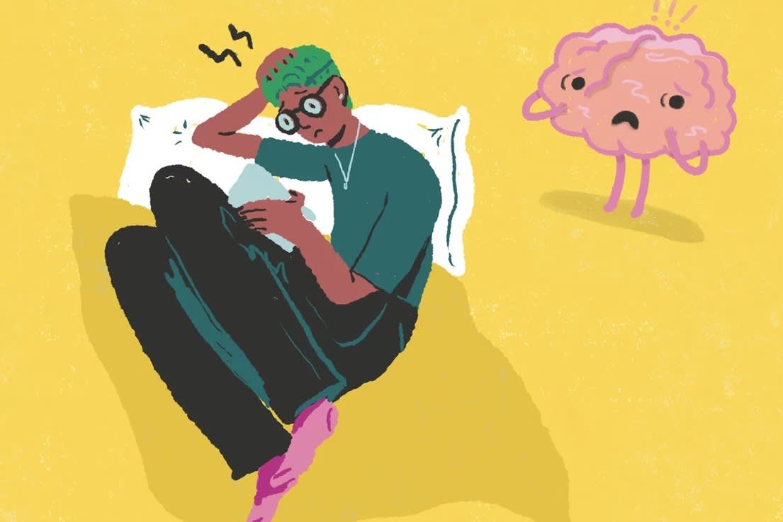A person with green hair and glasses sits on a bed, looking stressed while holding a tablet. Nearby, a worried cartoon brain stands on the yellow floor, both appearing anxious.