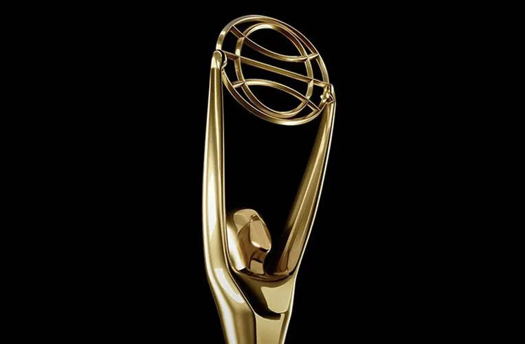 A gold trophy statue featuring a stylized human figure holding up a large ring, set against a plain black background.