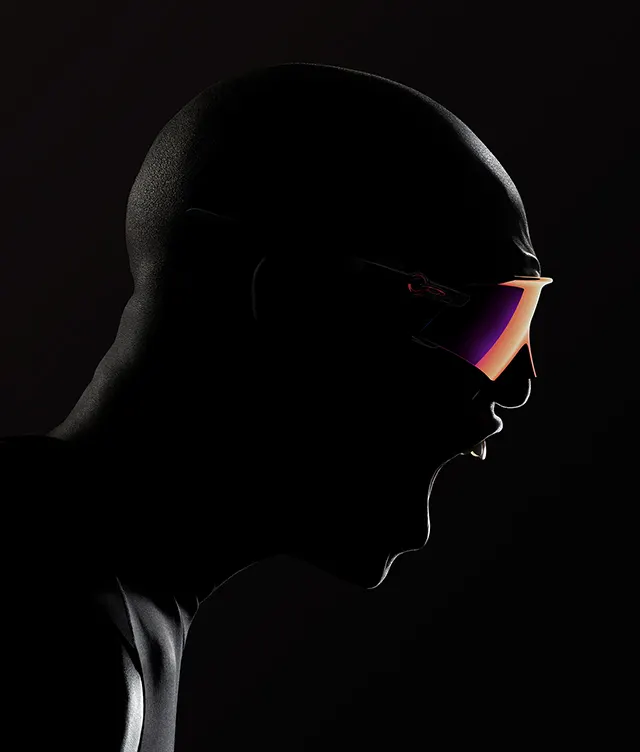 A dramatic side profile of a person in a black bodysuit, mouth open as if shouting, wearing large, reflective, futuristic sunglasses against a dark background.