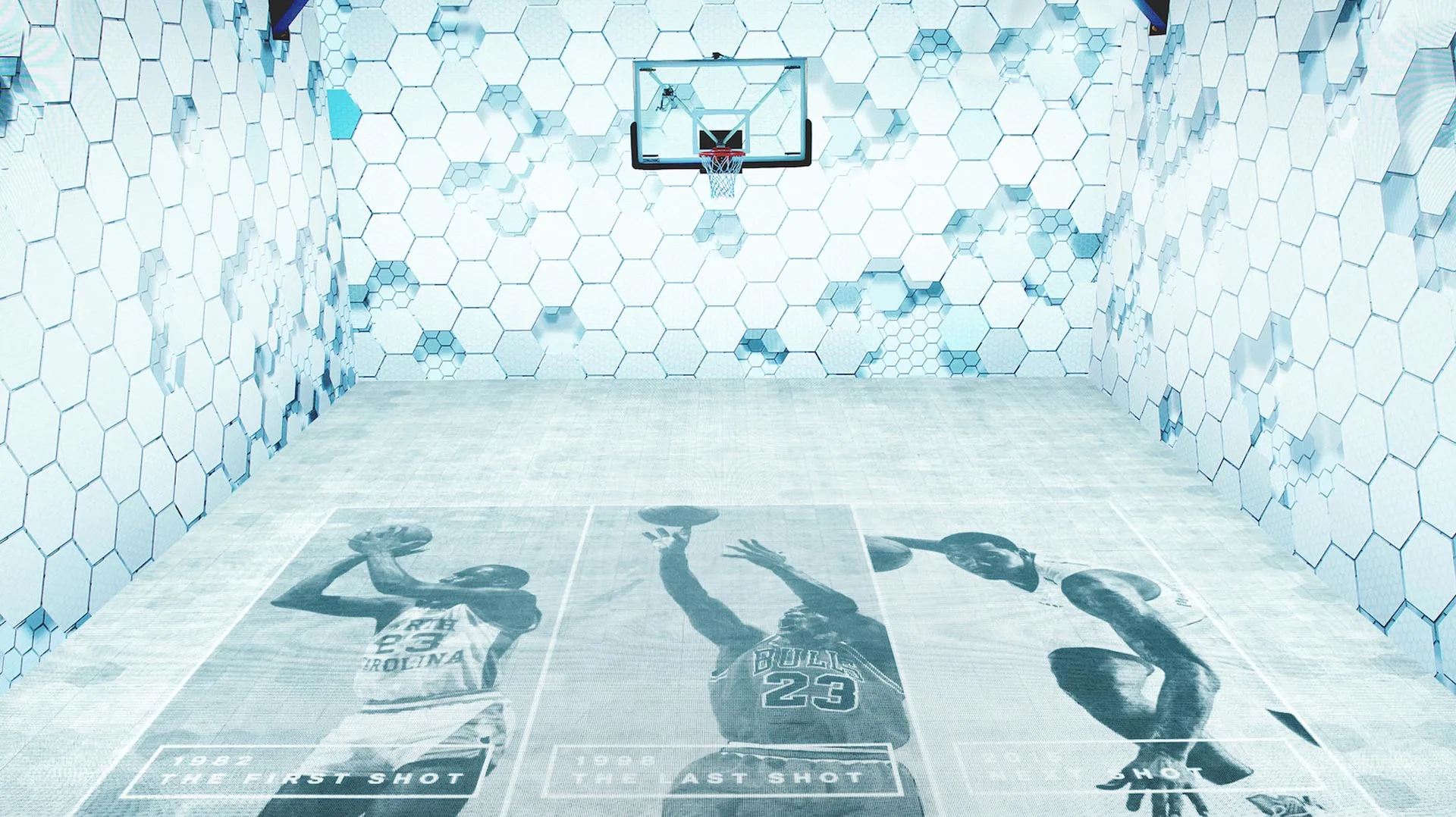 A basketball court with hexagonal patterned walls and floor. Three large images of a player shooting, labeled 1982 The First Shot, 1998 The Last Shot, and 1988 The Shot, are printed on the court floor.