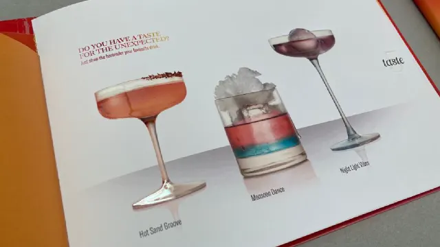 An open menu shows three cocktails: Hot Sand Groove in a coupe glass, Moonbow Dance in a rocks glass with ice, and Night Light Vision in a stemmed glass with a cherry. The text highlights a taste for the unexpected.