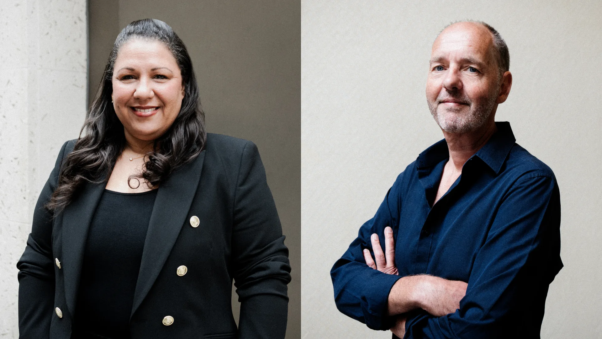 Two people stand side by side against a plain background. The woman on the left wears a black blazer and smiles with her hand on her hip. The man on the right, in a dark shirt, stands with arms crossed and a slight smile.