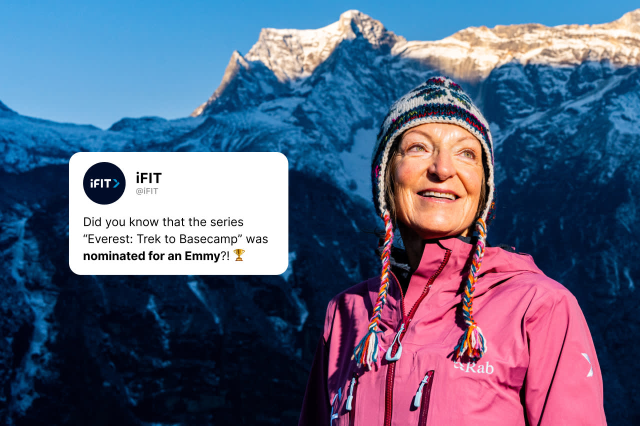 A smiling woman in a colorful winter hat and pink jacket stands outdoors with snowy mountains in the background. A tweet overlay says the series “Everest: Trek to Basecamp” was nominated for an Emmy.