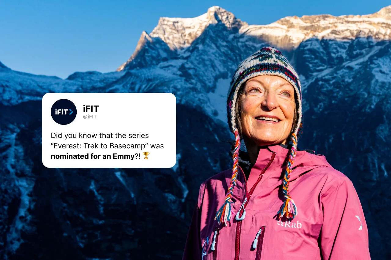 A smiling woman in a colorful winter hat and pink jacket stands outdoors with snowy mountains in the background. A tweet overlay says the series “Everest: Trek to Basecamp” was nominated for an Emmy.