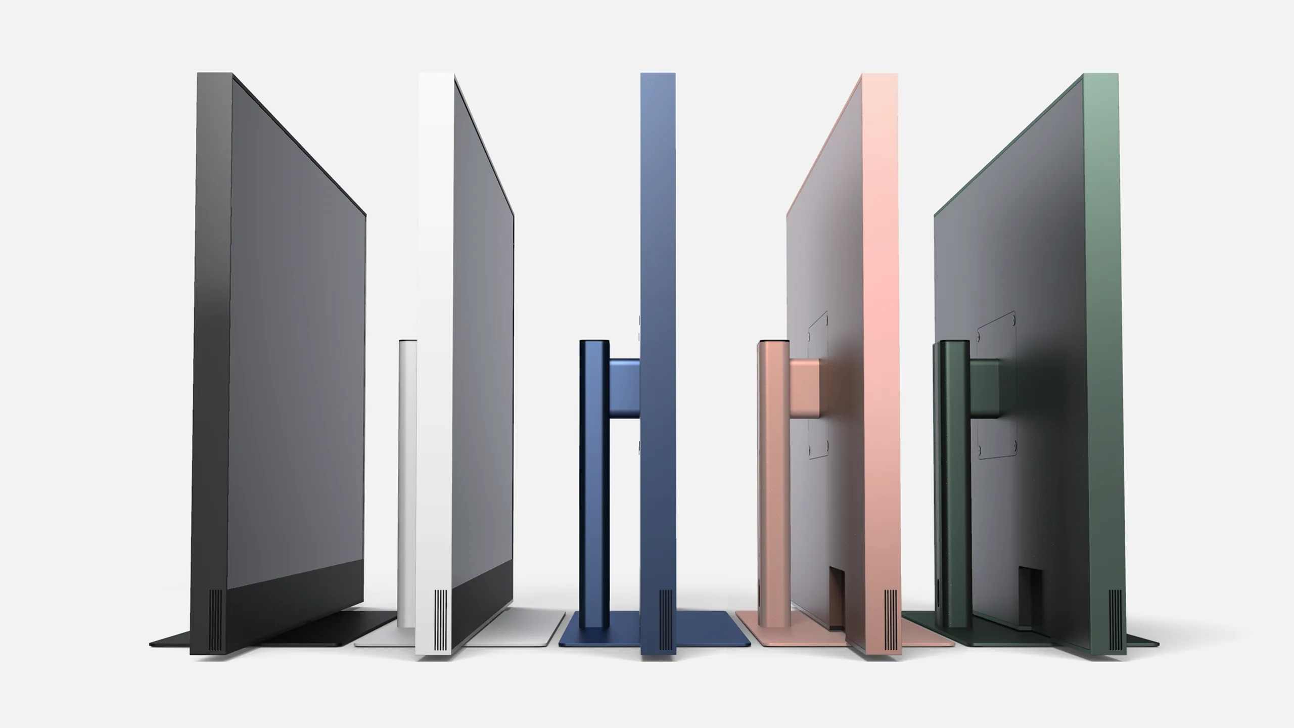 Five slim, modern monitors in different colors (black, white, blue, pink, and green) are shown from the side and back angles, standing upright in a row against a light background.