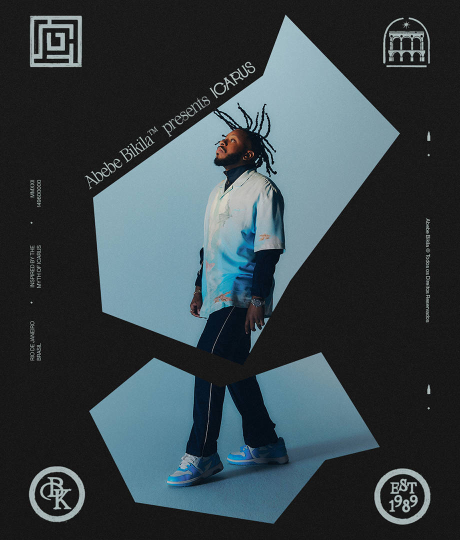 A man with braids stands confidently in a geometric frame, wearing a light blue shirt, dark pants, and sneakers. The text reads Abebe Bikila™ presents ICARUS with various logos and design elements around the border.