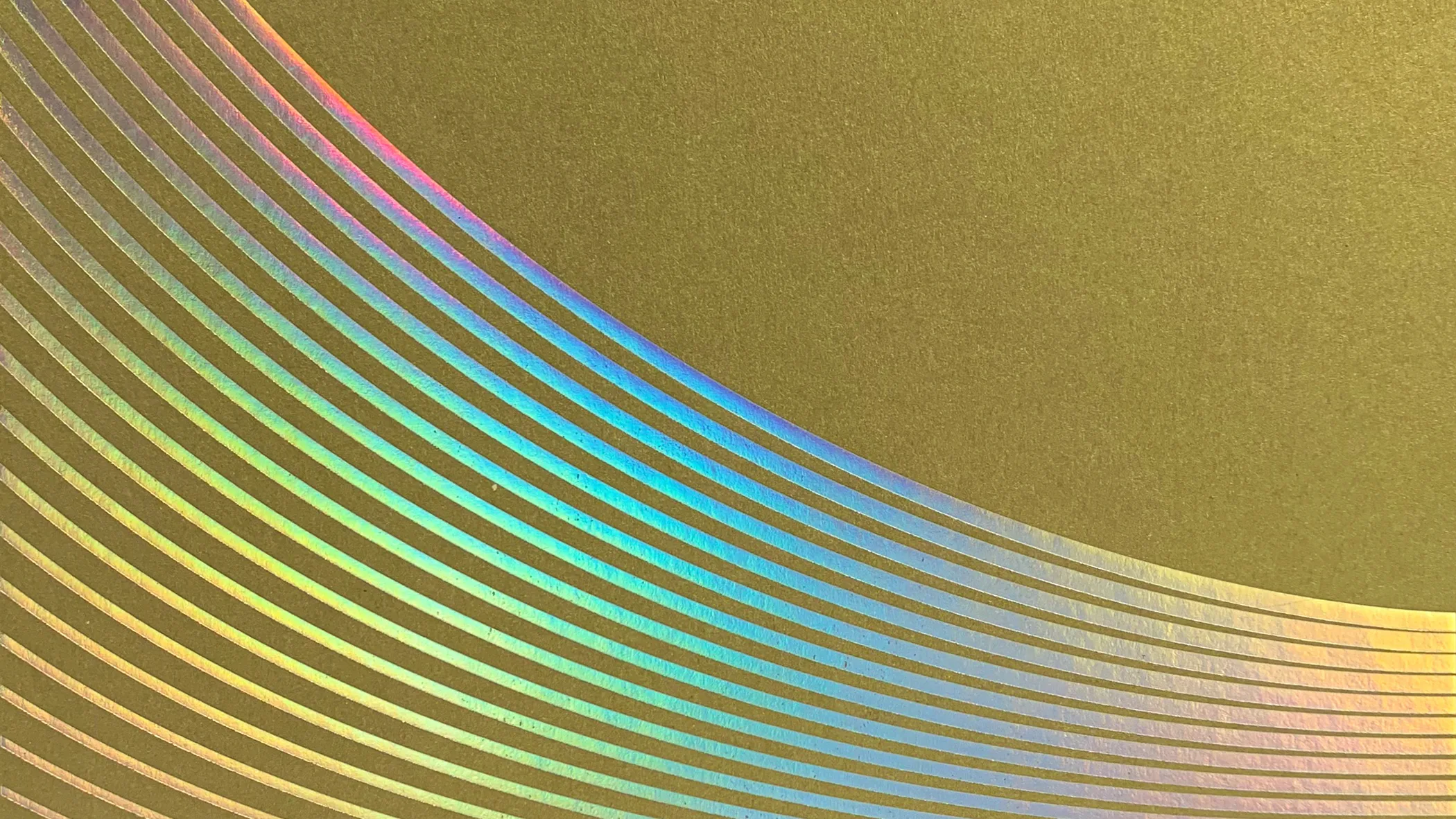 A metallic gold surface with a pattern of curved, parallel iridescent lines creating a rainbow effect across the bottom left corner.