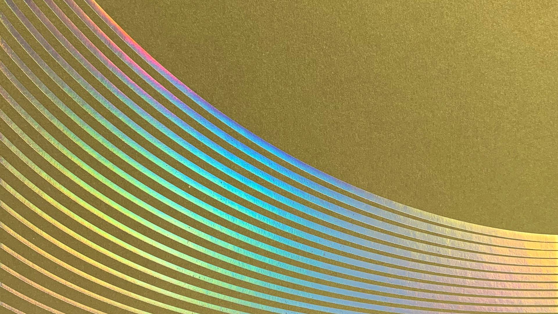 A metallic gold surface with a pattern of curved, parallel iridescent lines creating a rainbow effect across the bottom left corner.