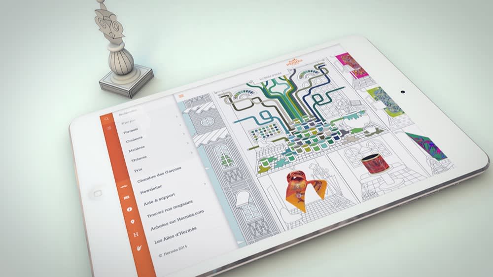 A white tablet displaying a colorful digital drawing app lies on a light surface. Next to it stands a detailed chess piece resembling a bishop. The screen shows partially colored geometric and nature-themed artwork.
