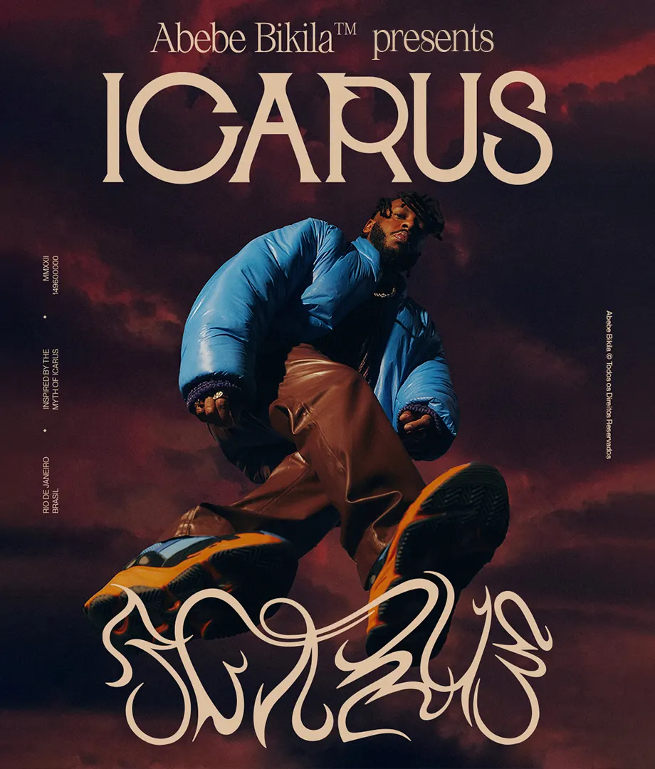 A person in a blue puffer jacket and brown pants poses with one foot forward against a dramatic, cloudy red sky. Large text reads Abebe Bikila™ presents ICARUS, with stylized graffiti at the bottom.