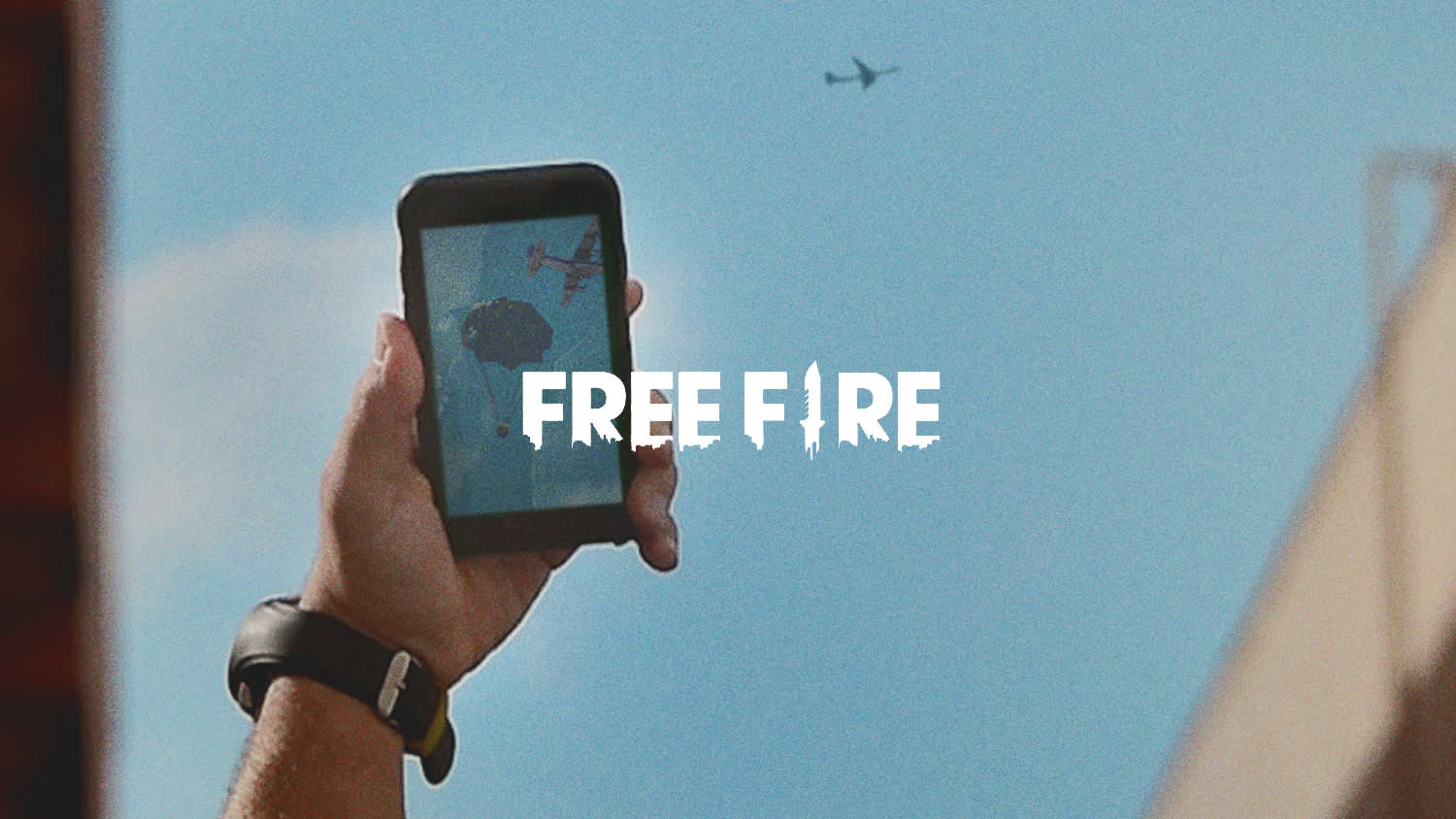 A hand holding a smartphone with an aircraft on the screen, against a blue sky with a plane flying above; FREE FIRE is written in bold white letters across the image.