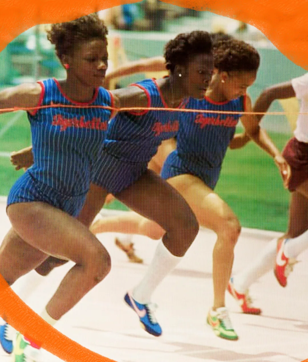 Three female athletes in blue striped uniforms leap over a finish line on a track during a race, with motion showing their effort and focus. An orange border partially frames the image.
