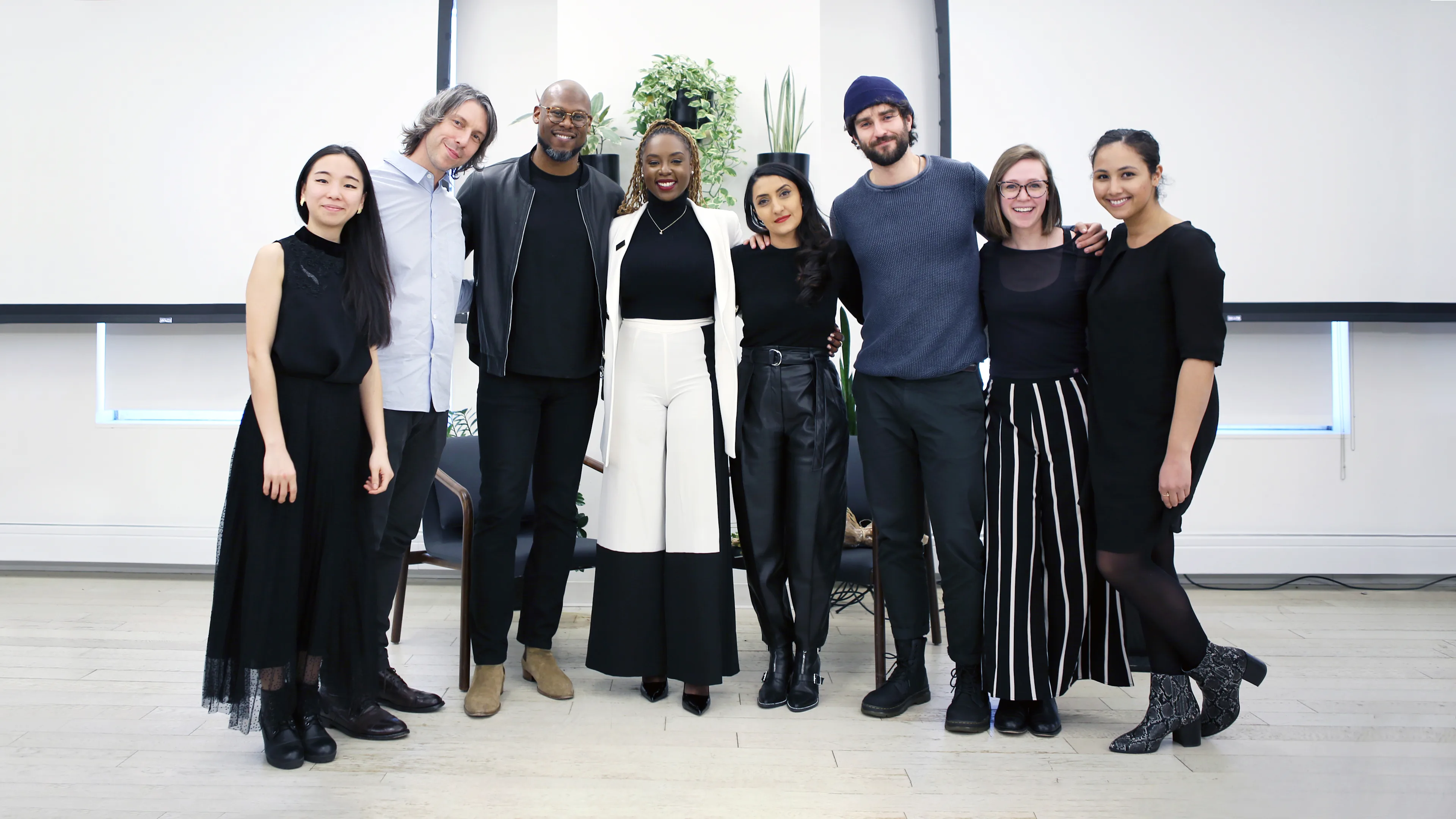 A group of eight AKQA employees stand in a row with their arms around each other.