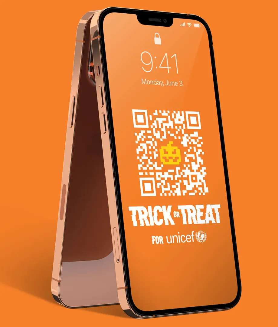 Two rose gold smartphones stand back-to-back against an orange background. The front screen displays a Halloween-themed QR code, a pumpkin icon, and the text Trick or Treat for UNICEF in white letters.