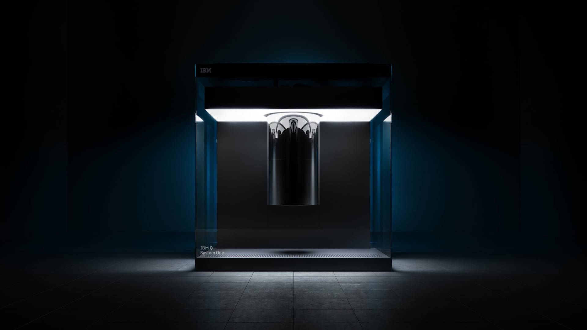 A futuristic, illuminated glass cube enclosure contains a cylindrical, metallic quantum computer suspended in the center, with the IBM logo visible on the top left corner in a dark, minimalistic setting.
