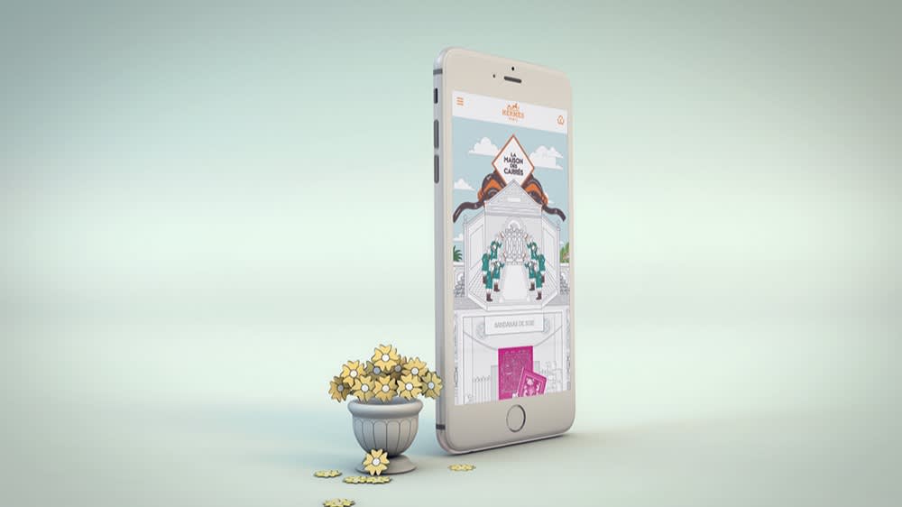 A smartphone displaying an illustrated gate is standing upright next to a small decorative pot filled with yellow flowers, with some flowers scattered on the surface in front of a soft, light background.