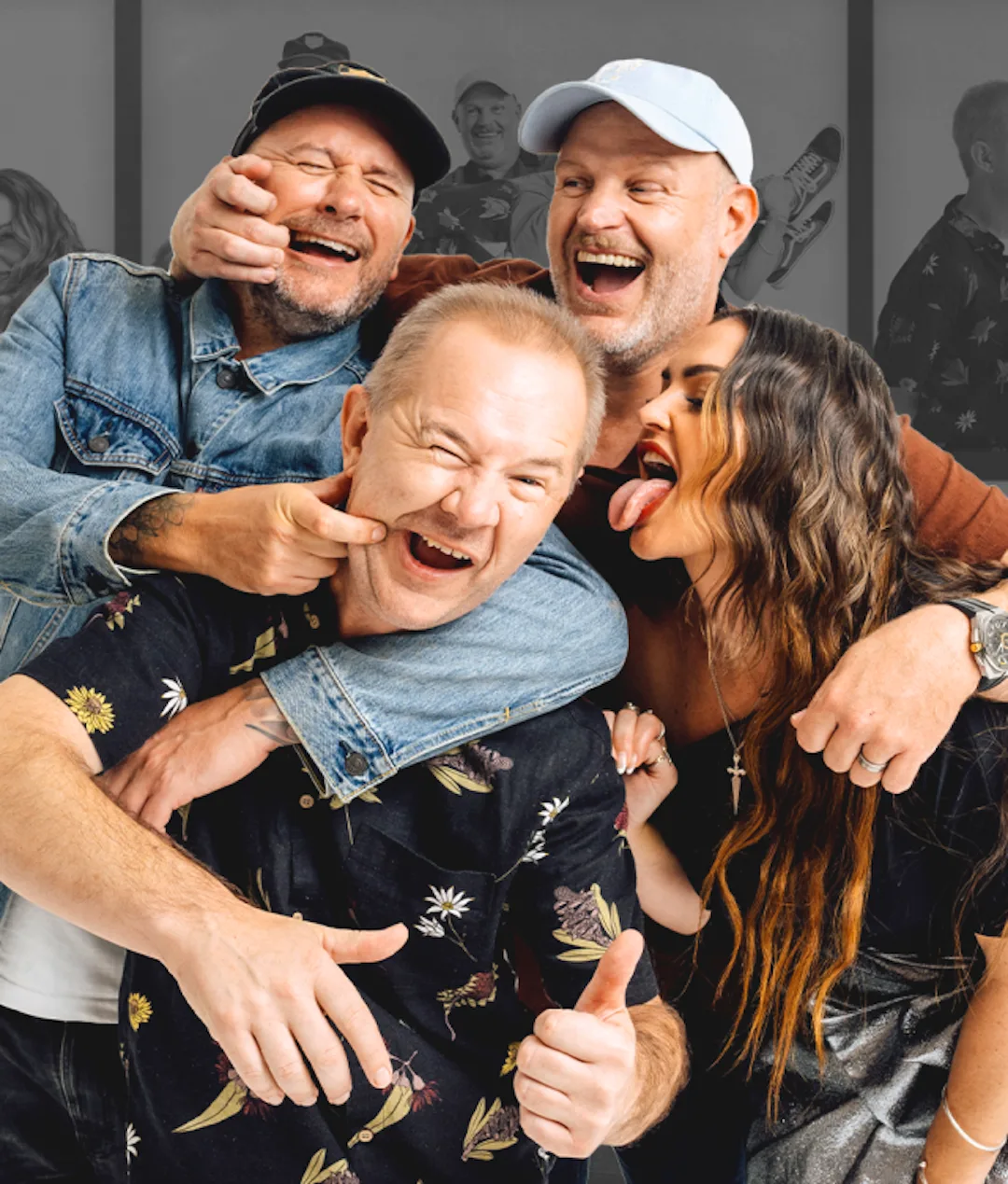 Four adults pose playfully together; three men and one woman. The men smile and laugh, while the woman sticks out her tongue, touching the cheek of the man in front. They appear to be having fun and joking around.