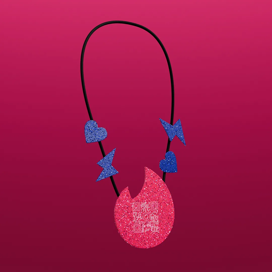 A necklace with a black cord features a glittery red pendant shaped like a flame with a QR code, along with two blue hearts and two blue lightning bolts, set against a pink gradient background.