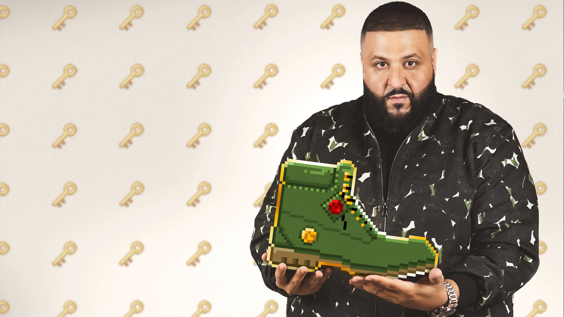 A man with a beard stands in front of a wall patterned with gold keys, holding a large green pixelated boot with both hands while looking at the camera.