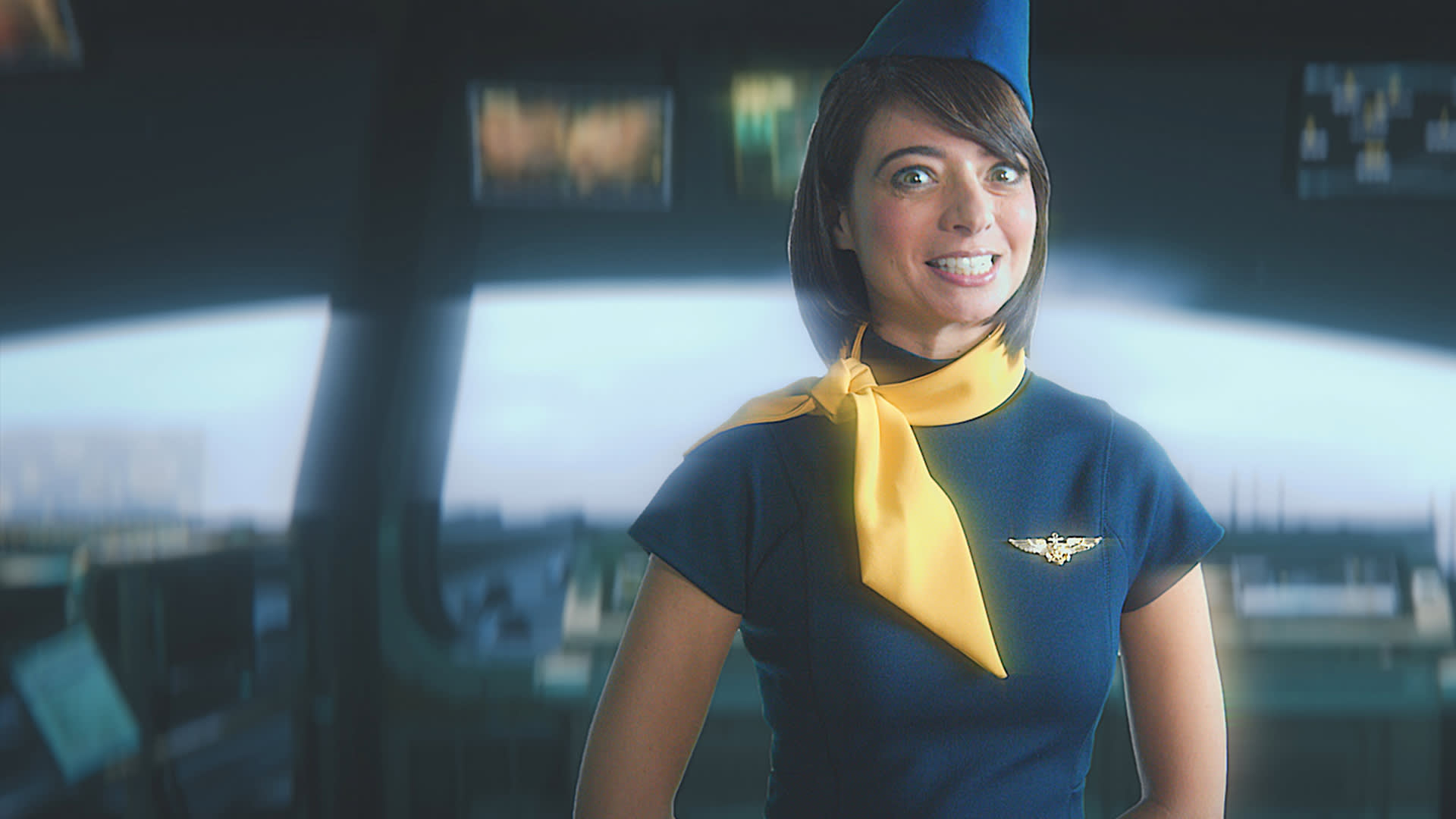 A smiling flight attendant in a navy blue uniform with a yellow scarf stands in front of an airplane cockpit, with blurred control panels in the background.
