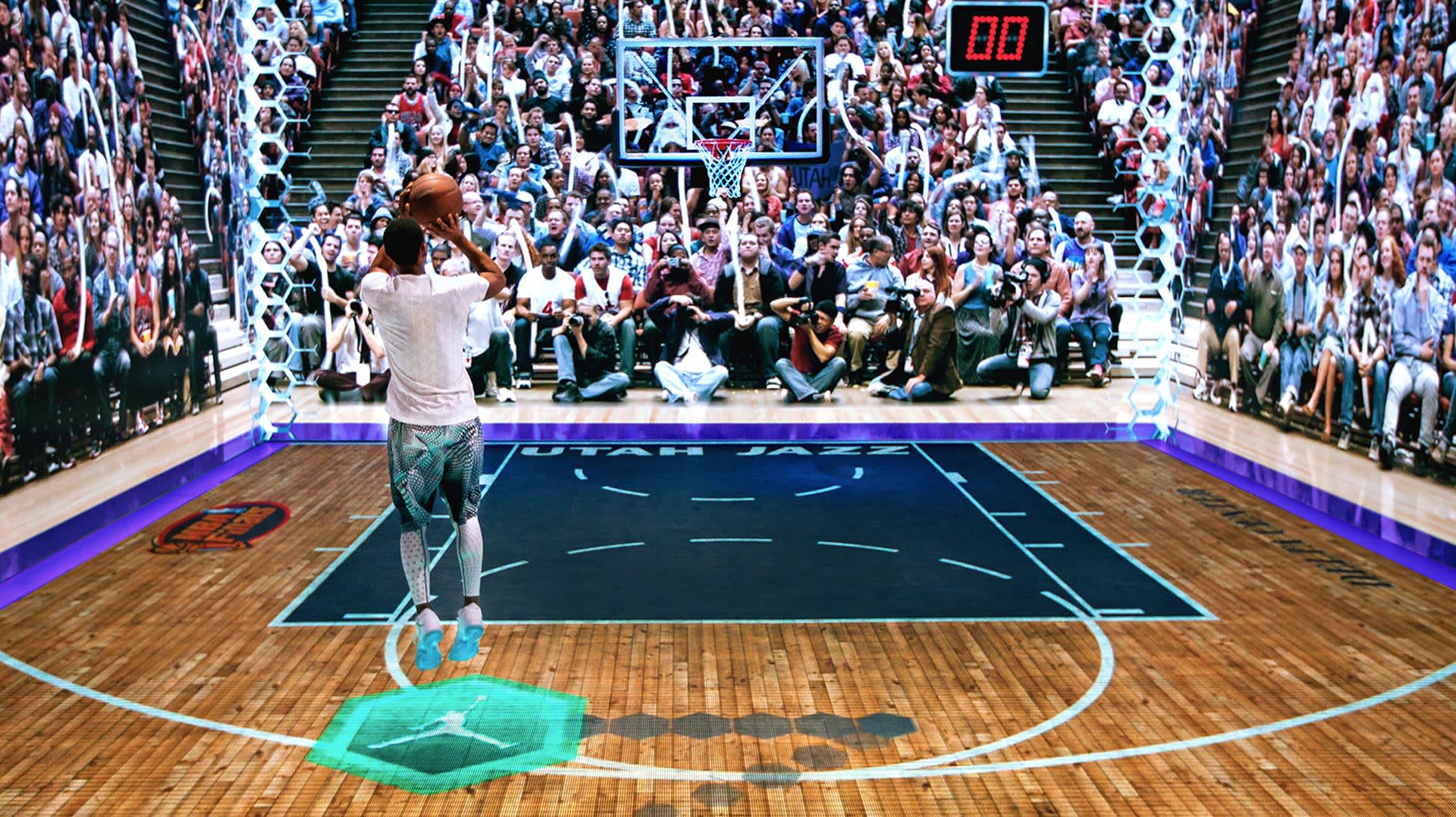 A basketball player in white shoots a jump shot on an indoor court, facing a large, digitally projected crowd. The scoreboard shows 0:00. The court features the Utah Jazz logo and high-tech augmented reality graphics.