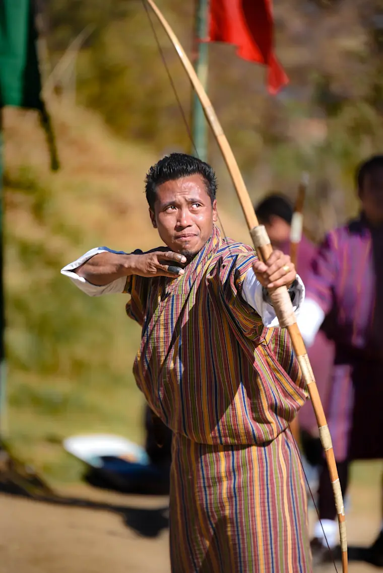 Een Bhutanese man die boogschiet (Gho dragend)