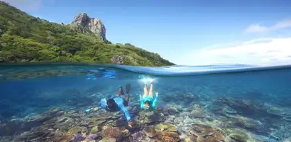 snorkelaar-boven-kleurig-koraalrif-met-eiland &middot; fiji-samoa-en-vanuatu