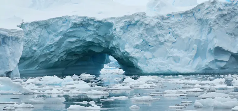 Een adembenemend uitzicht op een massieve ijsbrug die zich uitstrekt over een ijzige baai vol drijvend pakijs, omgeven door imposante gletsjerwanden in het Antarctische of arctische gebied.