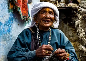 Inwoonster van de Brokpa-nederzettingen lacht naar de camera in traditionele kledij