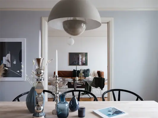 Matplats med träbord, designlampa och stilrena detaljer som öppnar upp mot ett harmoniskt vardagsrum.