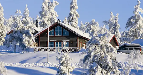 Fjällhus omgiven av snötäckta träd i vinterlandskap med vidsträckt utsikt och naturnära boendemiljö.