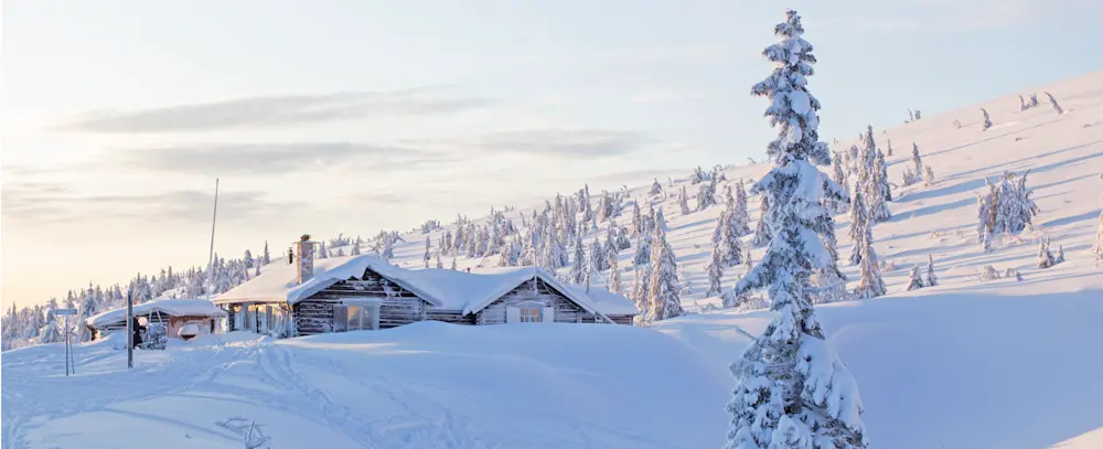 En snötäckt fjällstuga med utsikt över det vinterklädda fjällandskapet, där natur, avkoppling och friluftsliv möts.