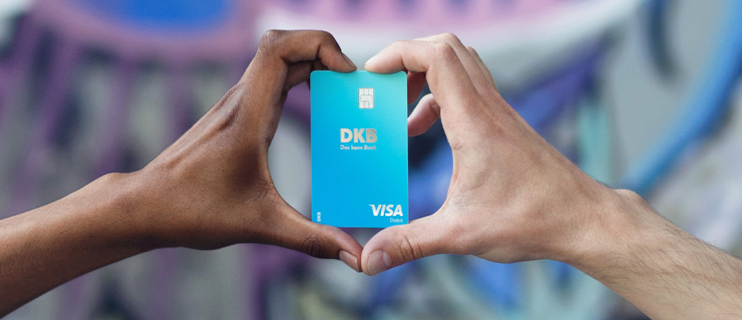 Zwei Händen formen Herz mit Visa Debitkarte in der Mitte