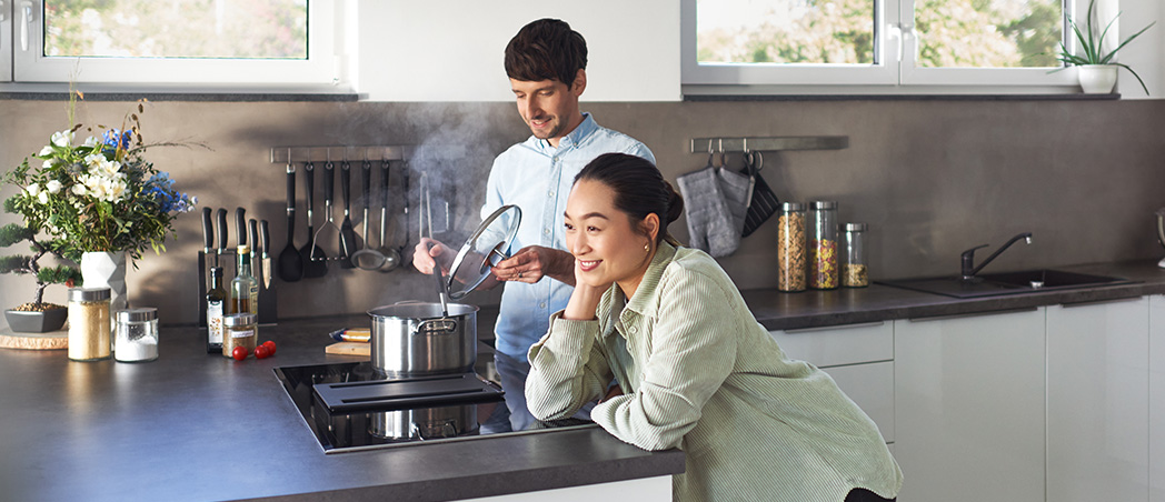 Junger Mann und junge Frau in moderner Küche beim Kochen