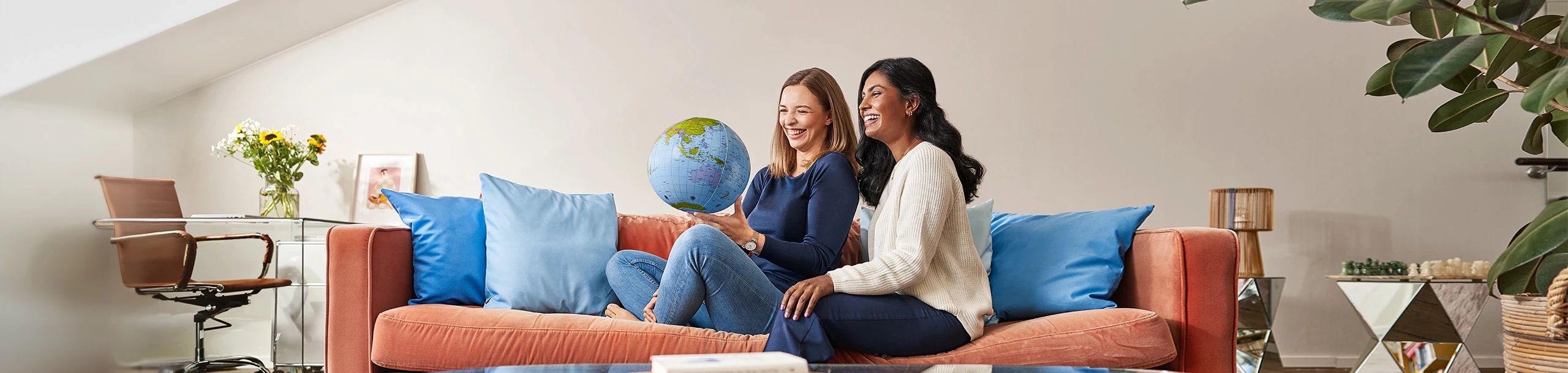 zwei Frauen auf Sofa mit Weltkugel