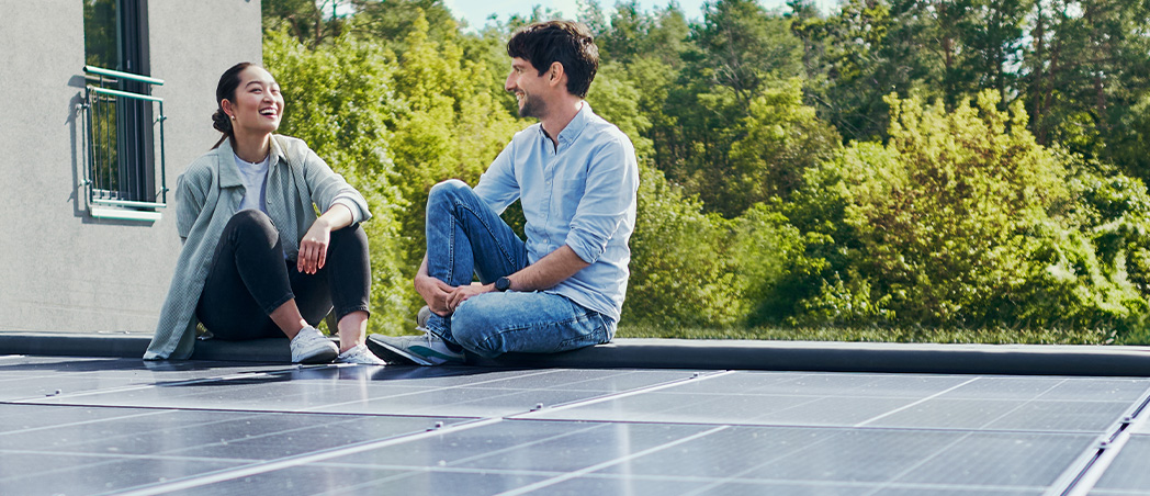 Eine Frau und ein Mann sitzen auf einem Solardach.
